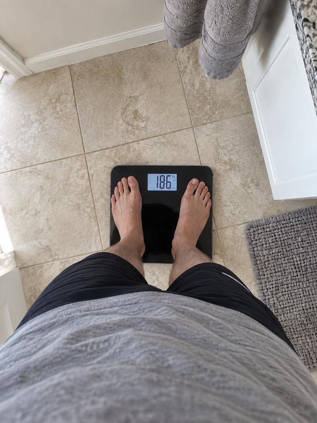 Robert S.’s published review photo showing him standing on a scale displaying 186